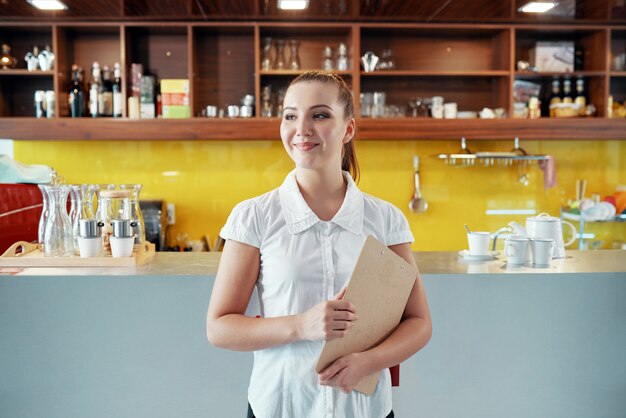 Contenido mujer con portapapeles gestionando negocio de cafetería