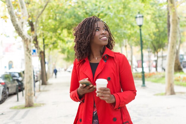 Contenido de mujer con teléfono inteligente y vaso de papel