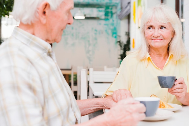 Contenido pareja de ancianos bebiendo té y tomados de la mano