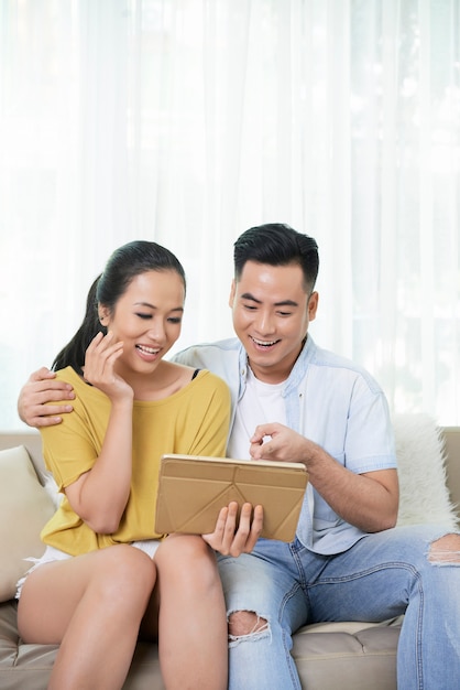 Contenido pareja mirando tableta y riendo