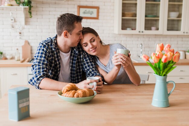 Contenido pareja uniéndose a la mesa y disfrutando del té