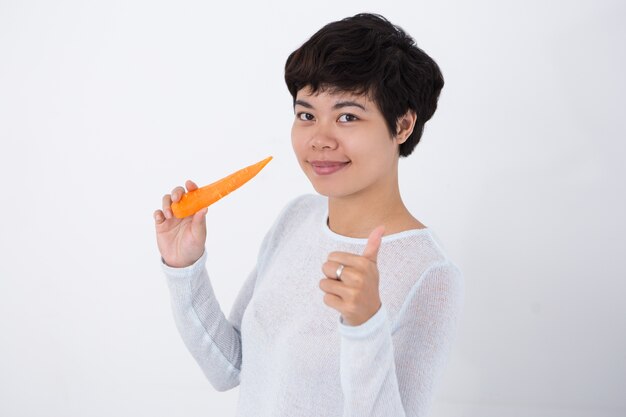 Content Girl Holding Carrot y mostrando pulgar hacia arriba