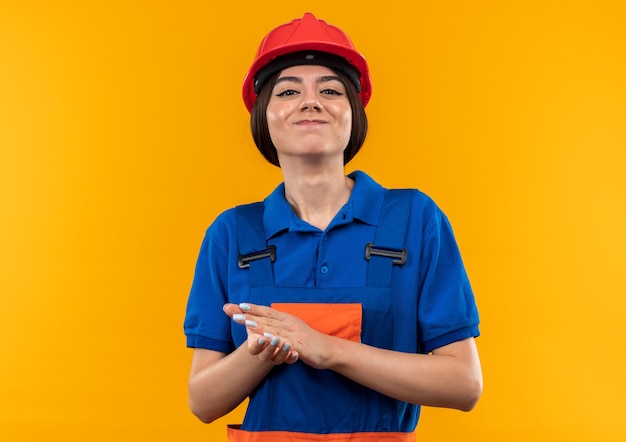 Contento mirando a la cámara joven constructor mujer en uniforme tomados de la mano juntos