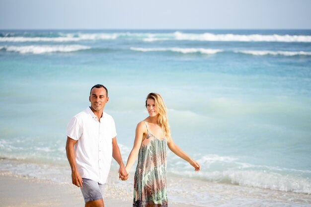 Contento pareja caminando en la playa de vacaciones