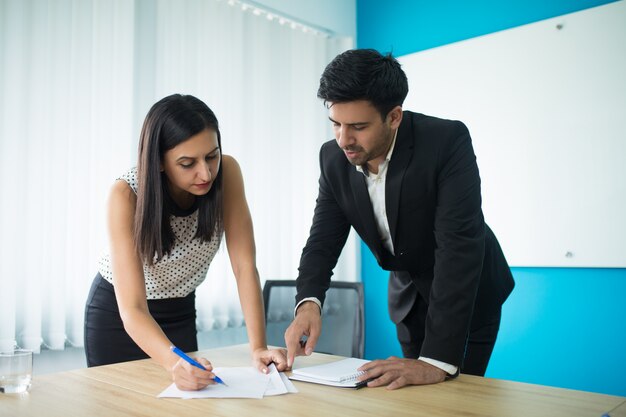 Contrato de firma serio del hombre de negocios y de la empresaria