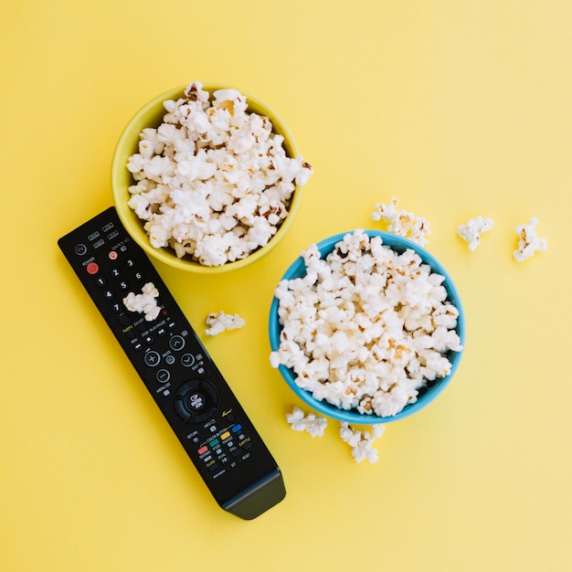 Foto gratuita control remoto de tv cerca de cuencos con palomitas de maíz