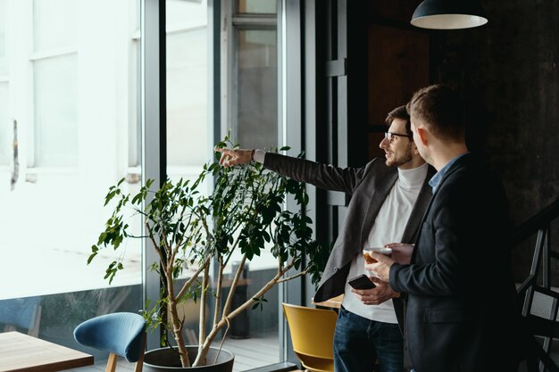 Conversación de hombres de negocios, señalando con la mano a la ventana