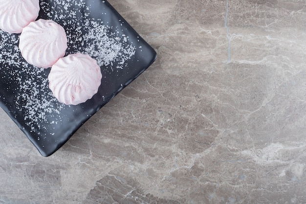 Cookies en un plato negro sobre superficie de mármol