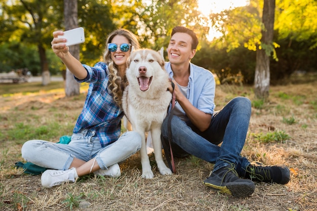 Cool elegante pareja joven jugando con perro en el parque