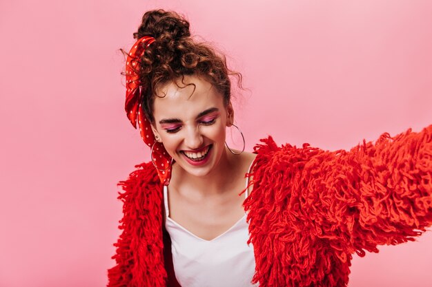 Cool girl en abrigo rojo y camiseta blanca riendo en rosa