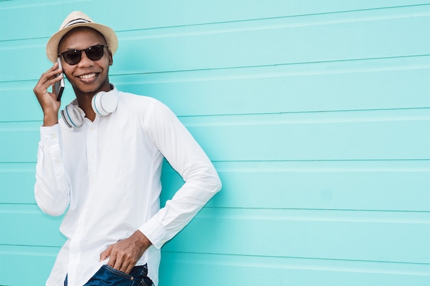 Cool hombre afroamericano llamando a alguien a través de su teléfono contra un fondo azul claro