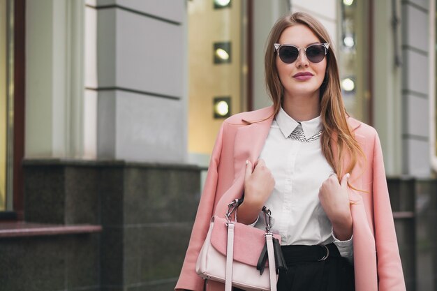 Cool joven elegante hermosa mujer caminando en la calle, con abrigo rosa, bolso, gafas de sol, camisa blanca, falda negra, traje de moda, tendencia de otoño, sonriendo feliz, accesorios