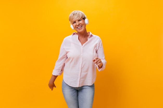 Cool lady en auriculares sonriendo sobre fondo naranja