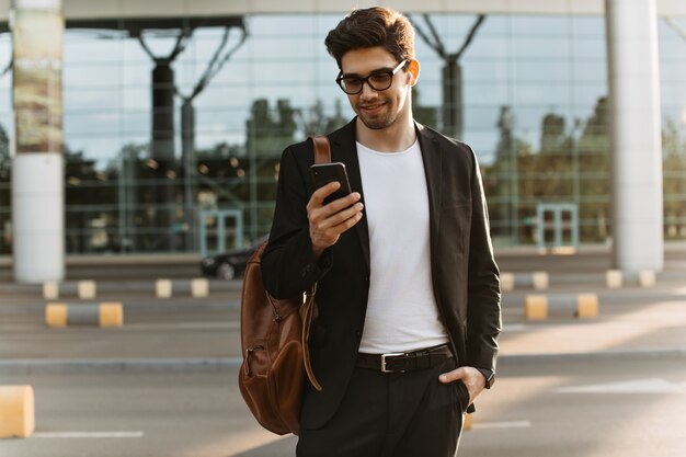 Cool morena hombre en conversaciones de anteojos en el teléfono