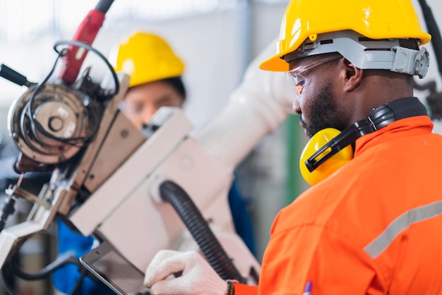 Cooperación de ingenieros, técnico masculino y femenino, control de mantenimiento, relé, sistema de brazo robótico, soldadura con tableta portátil para controlar la calidad, operación, proceso, trabajo, industria pesada, 40 fábrica de fabricación.