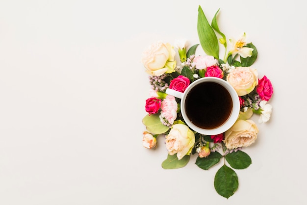 Copa con bebida en medio de la composición de flores