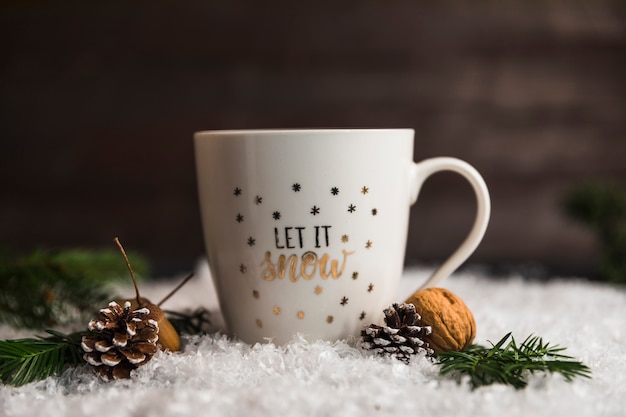 Foto gratuita copa cerca de ganchos, nueces y ramitas en la nieve