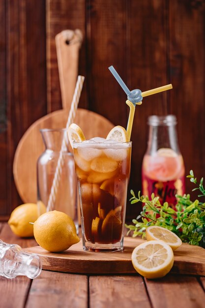 Una copa de cóctel con cubitos de hielo y limón y dos tubos de paja de plástico.