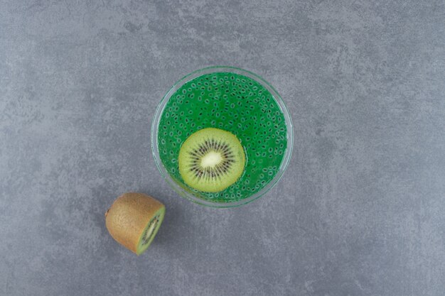 Una copa de cóctel de jugo de kiwi con una rodaja de fruta.