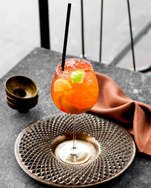 Una copa de cóctel de naranja fría servida en un hermoso plato de bronce.