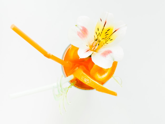 Copa de cóctel de naranja con paja y orquídea