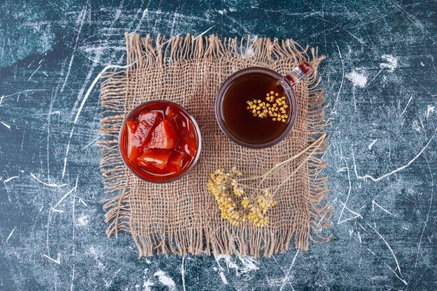 Copa de cóctel rojo con rodajas de frutas sobre la superficie de mármol.