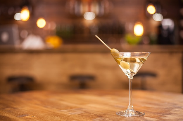 Copa de martini seco en un restaurante sobre una mesa de madera. Interior vintage de lujo