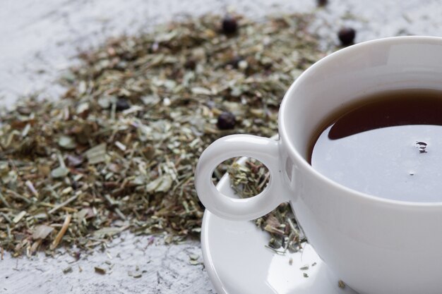 Copa con té con limón y hierbas secas sobre fondo de madera