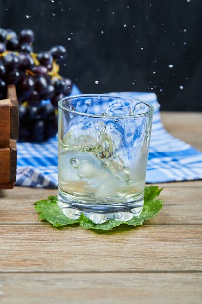 Una copa de vino blanco en una mesa de madera con uvas. Foto de alta calidad