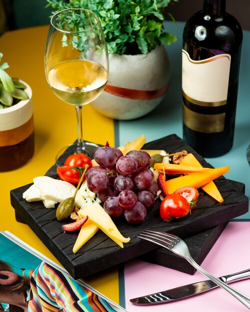 Copa de vino servido con uva, queso y tomate.