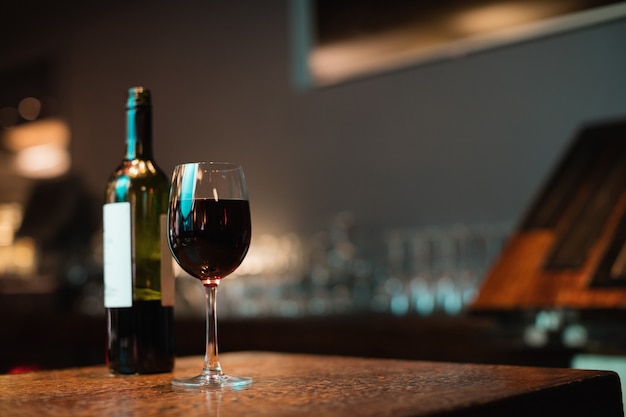 Copa de vino tinto y botella en barra de bar
