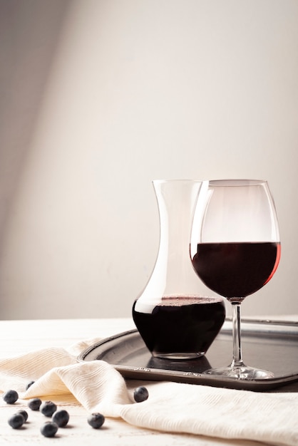 Copa de vino tinto con jarra en una bandeja
