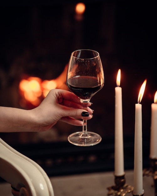 Una copa de vino tinto rodeado de velas en un ambiente romántico.