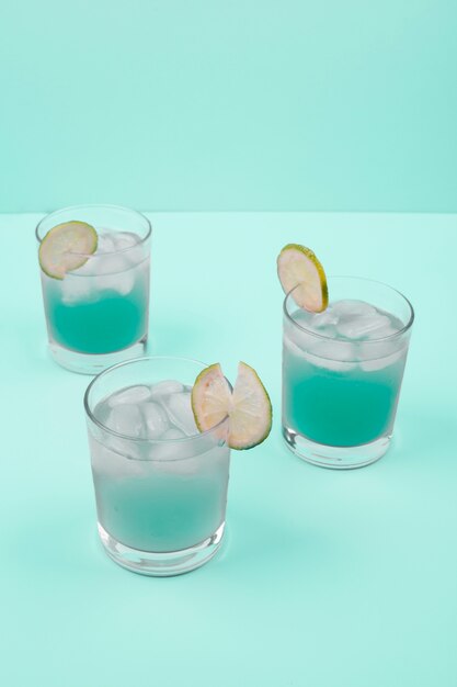 Copas de cóctel con cubitos de hielo y rodaja de limón sobre fondo de menta