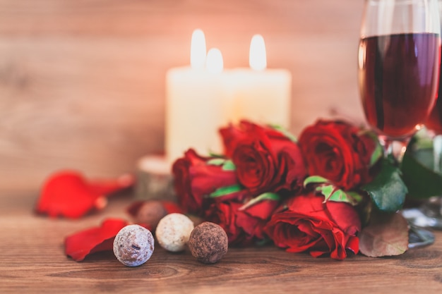 Copas de vino con velas encendidas y un ramo de rosas