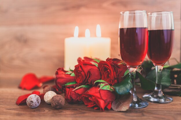 Copas de vino con velas encendidas y un ramo de rosas