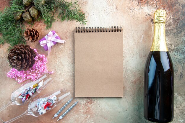 Copas de vino de vista superior con pequeños regalos y una botella de champán sobre fondo claro