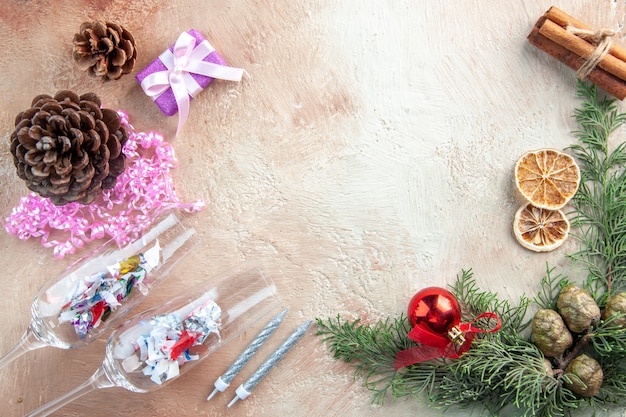 Copas de vino de vista superior con pequeños regalos y conos sobre fondo claro