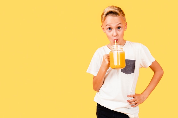 Foto gratuita copia espacio chico bebiendo naranja fresca