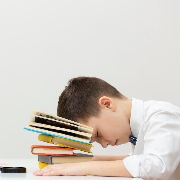 Foto gratuita copia espacio chico sentado con la cabeza en los libros