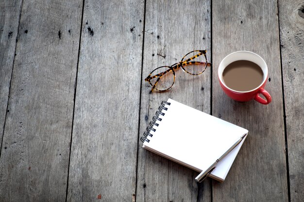 Copia espacio de cuaderno vacío y rojo taza de café sobre fondo de madera