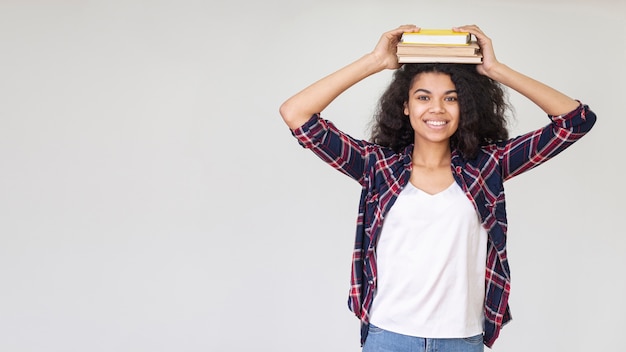 Copia-espacio juguetón adolescente con libro en la cabeza.