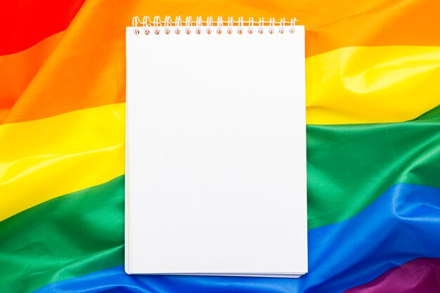 Copia espacio libreta vacía rodeada de bandera del orgullo del arco iris