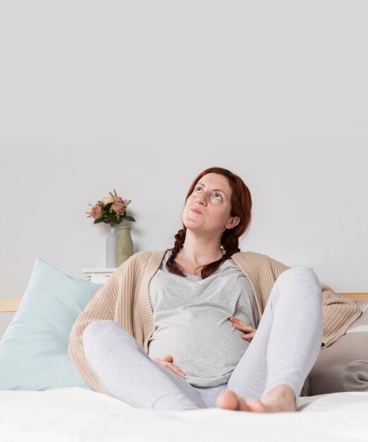 Copia espacio mujer embarazada en su casa en la cama