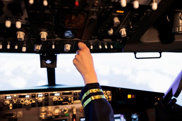 Copiloto femenino presionando botones y encendiendo el panel del tablero, volando un avión con comando de navegación y control. Usando la palanca del motor de potencia y la brújula de radar para despegar con el avión. De cerca.