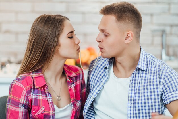 Cople encantador con espaguetis, beso en la cocina.