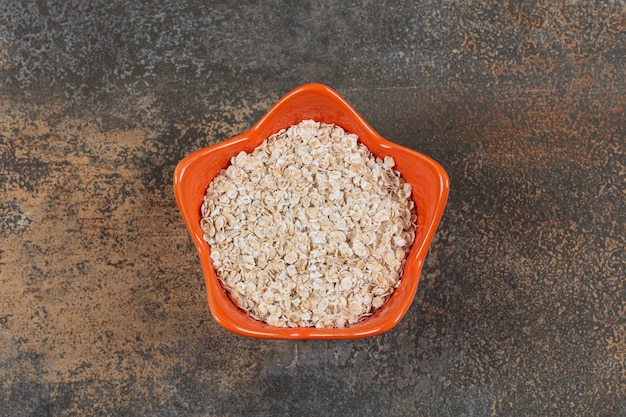 Copos de avena deliciosos en tazón de fuente naranja.