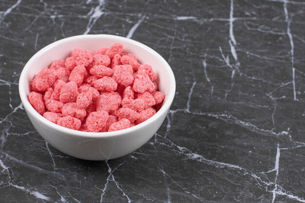 Copos de cereal de color rosa en un plato blanco.