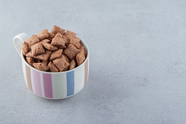 Copos de maíz de almohadillas de chocolate en taza de cerámica sobre fondo de piedra. Foto de alta calidad