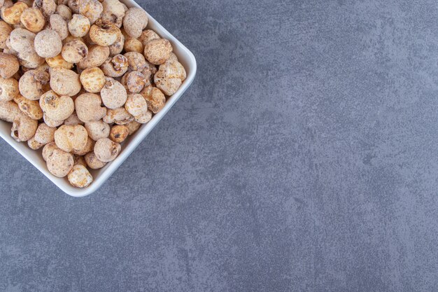 Copos de maíz dulces con muesli en un bol, sobre el fondo de mármol. Foto de alta calidad